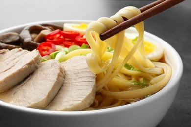 Noodle soup. Eating delicious ramen with chopsticks at table, closeup