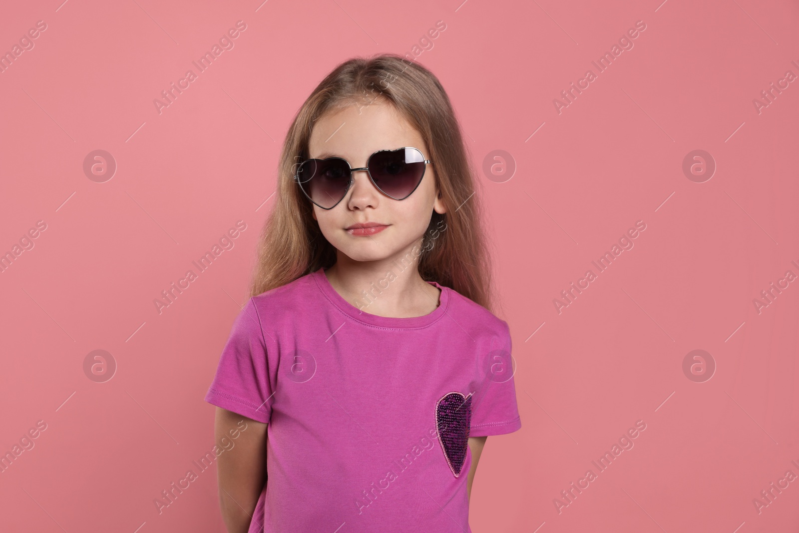 Photo of Girl wearing stylish sunglasses in shape of hearts on pink background