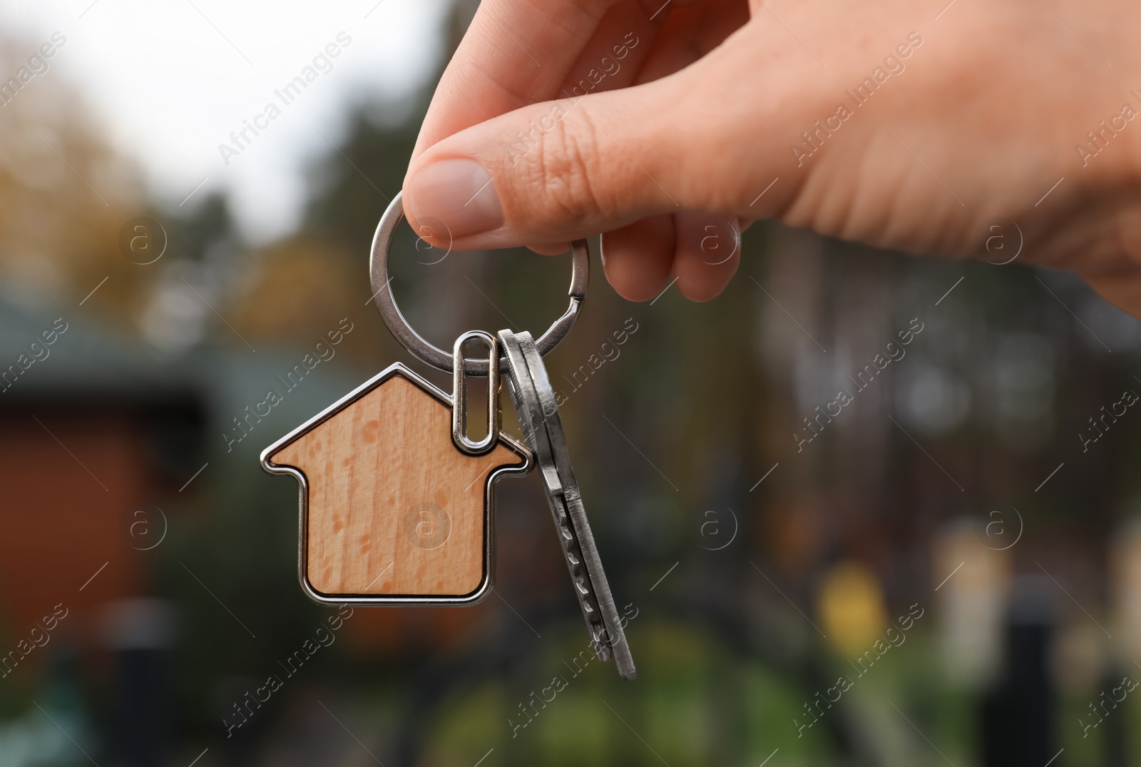 Photo of Woman holding house keys outdoors, closeup. Real estate agent