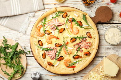 Photo of Delicious seafood pizza on white wooden table, flat lay