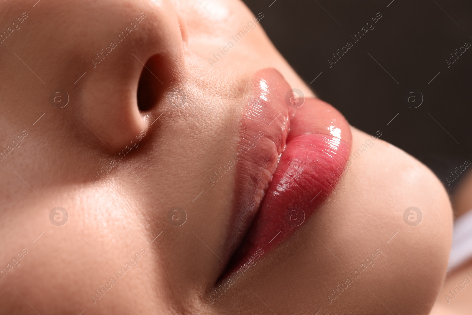 Photo of Young woman with permanent lip makeup in tattoo salon, closeup