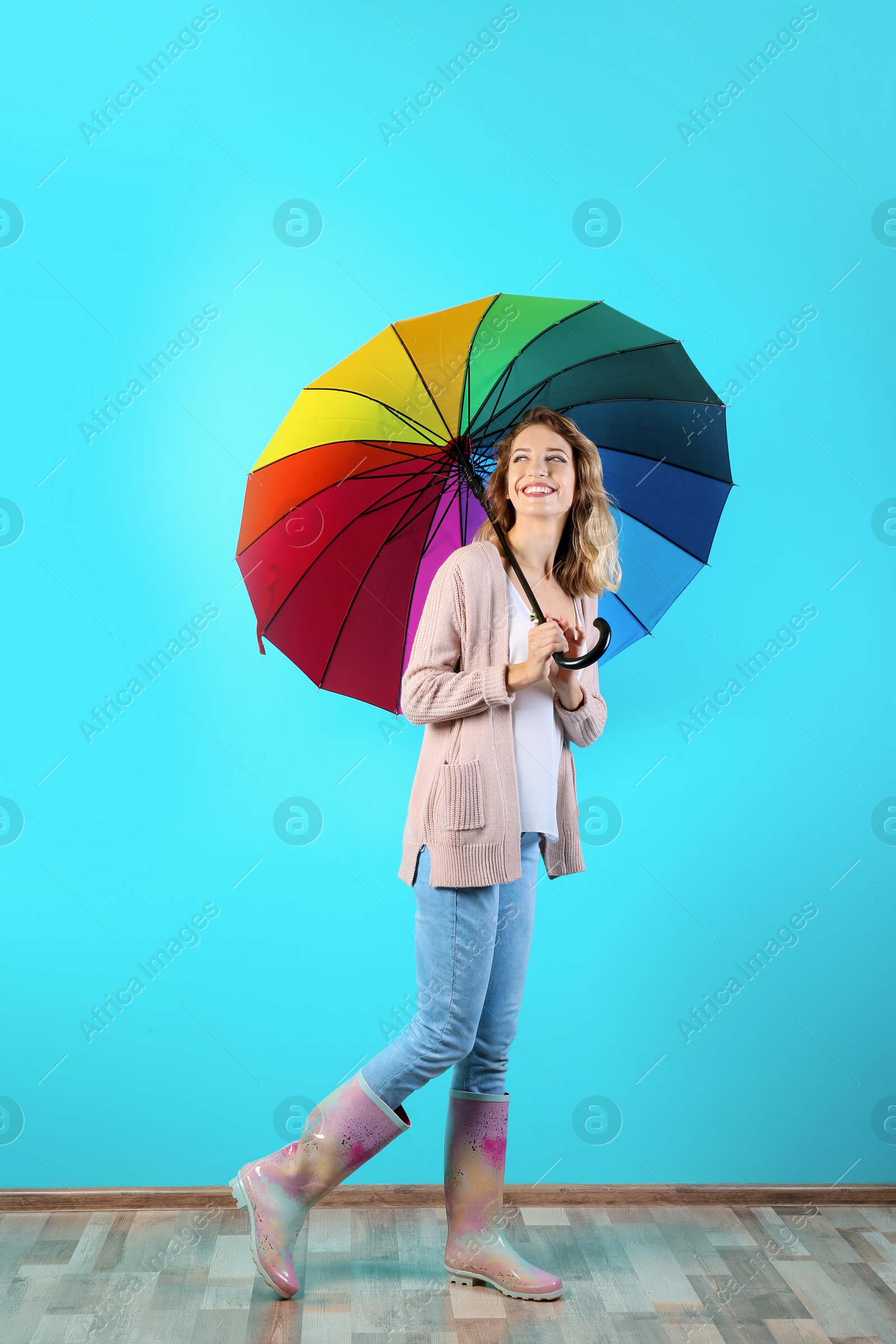 Photo of Woman with rainbow umbrella near color wall