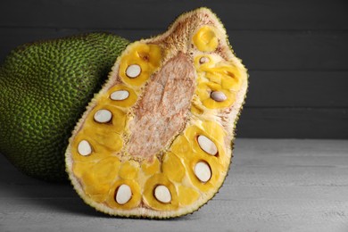 Photo of Delicious cut and whole exotic jackfruit on grey wooden table