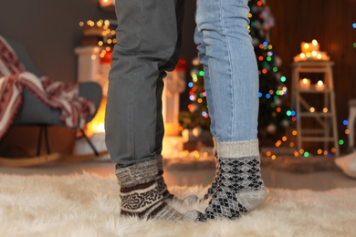 Photo of Young couple in warm socks celebrating Christmas at home