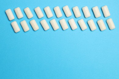 White bubble gums on blue background, flat lay. Space for text