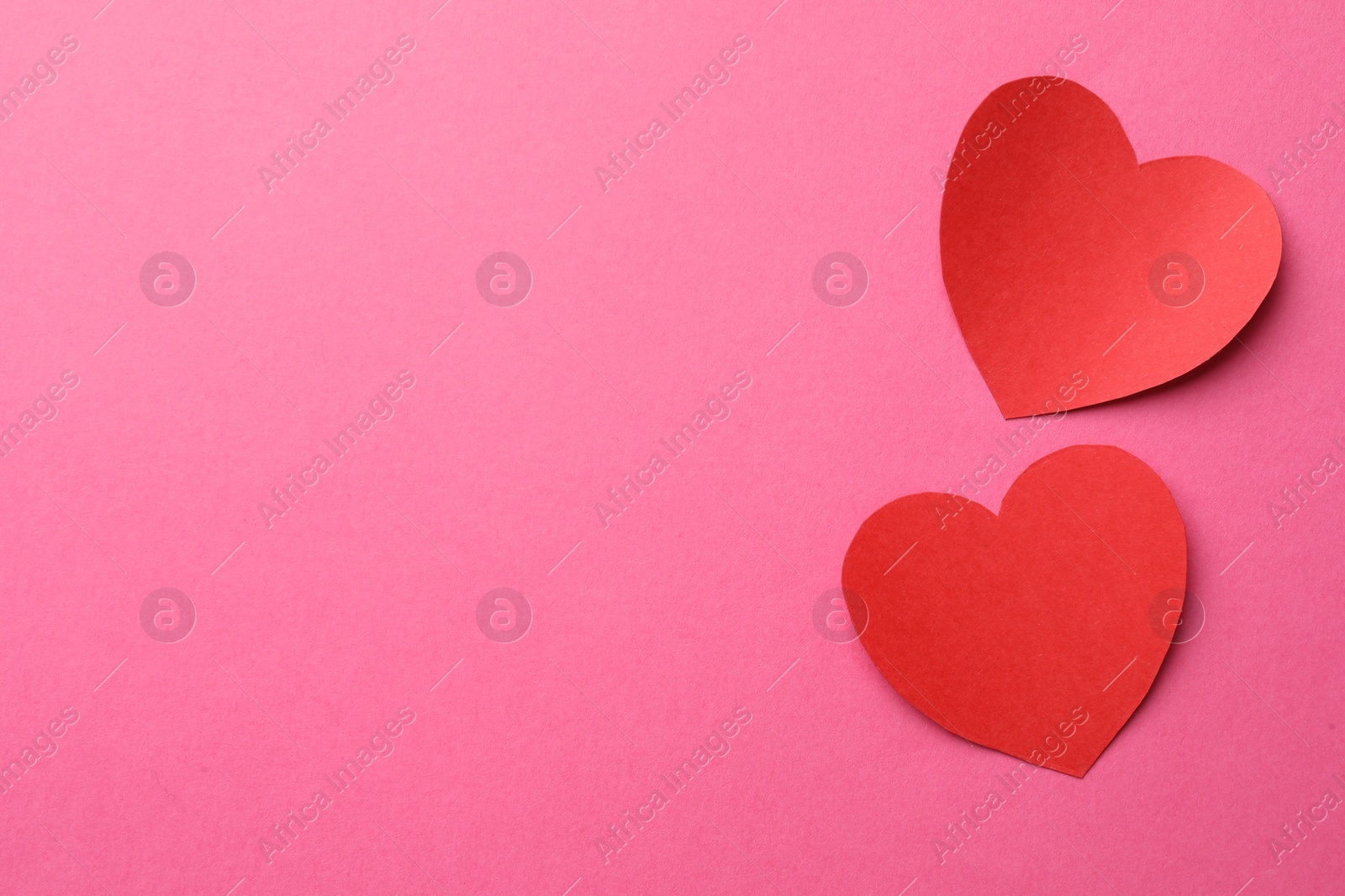 Photo of Red paper hearts on pink background, flat lay. Space for text