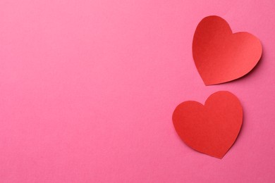 Photo of Red paper hearts on pink background, flat lay. Space for text