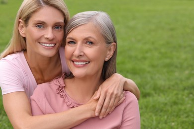 Happy mature mother and her daughter hugging outdoors