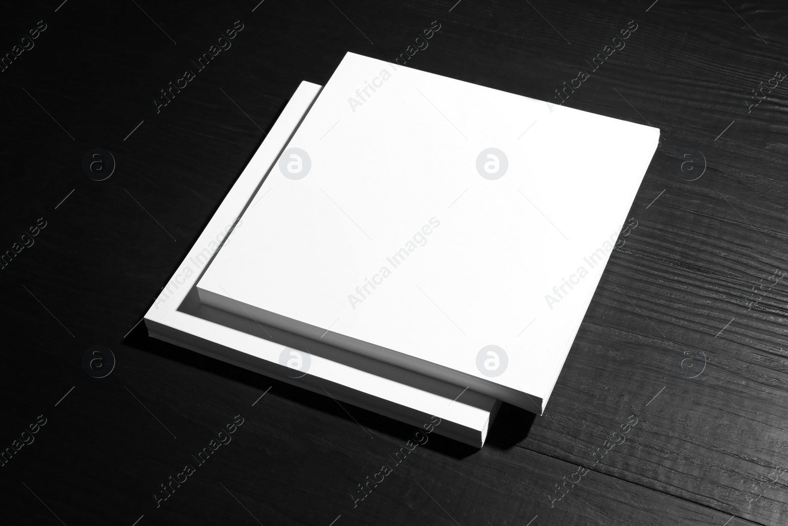 Photo of Stack of blank paper sheets for brochure on black wooden background. Mock up