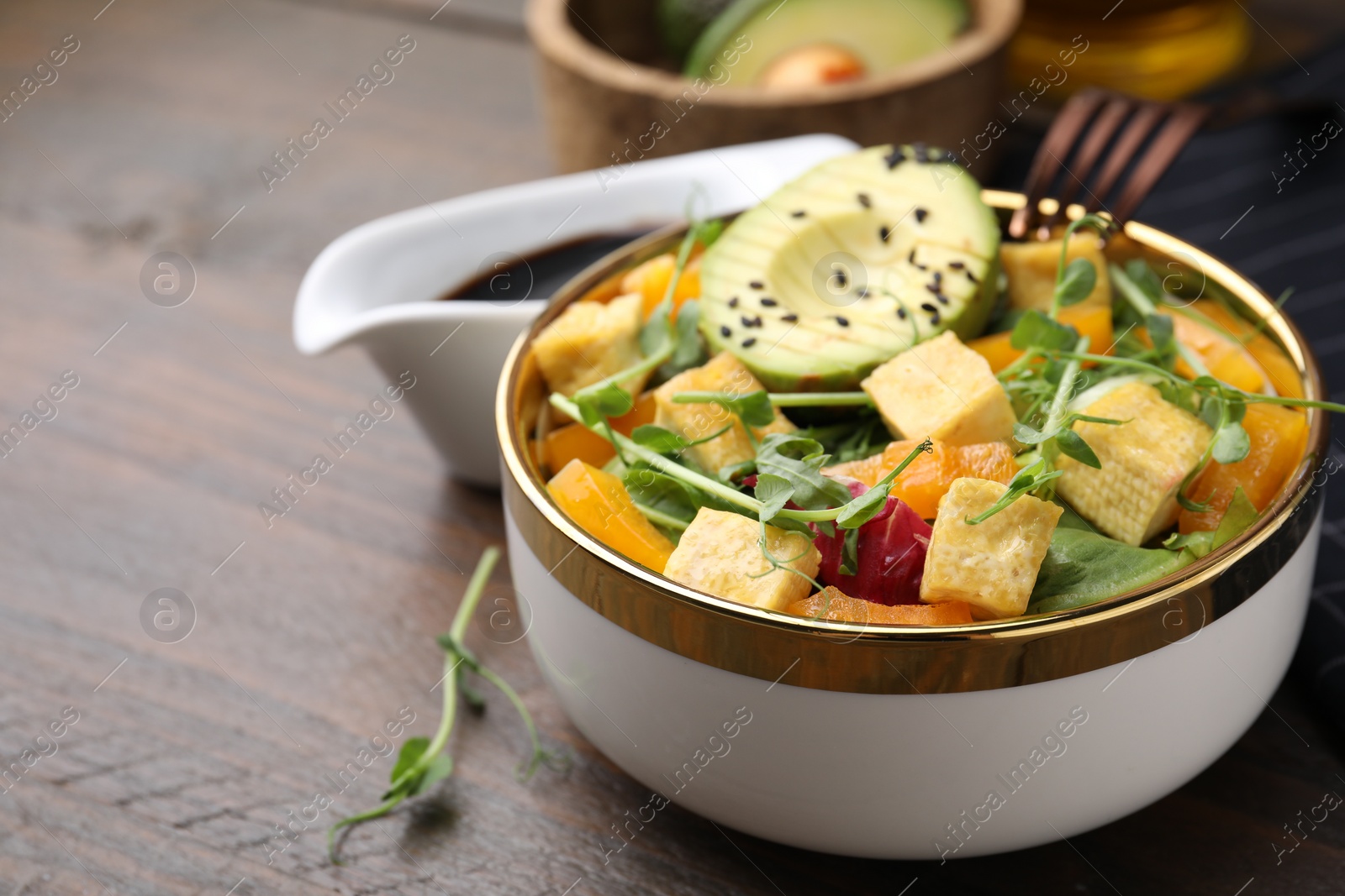 Photo of Delicious salad with tofu and vegetables on wooden table, closeup. Space for text