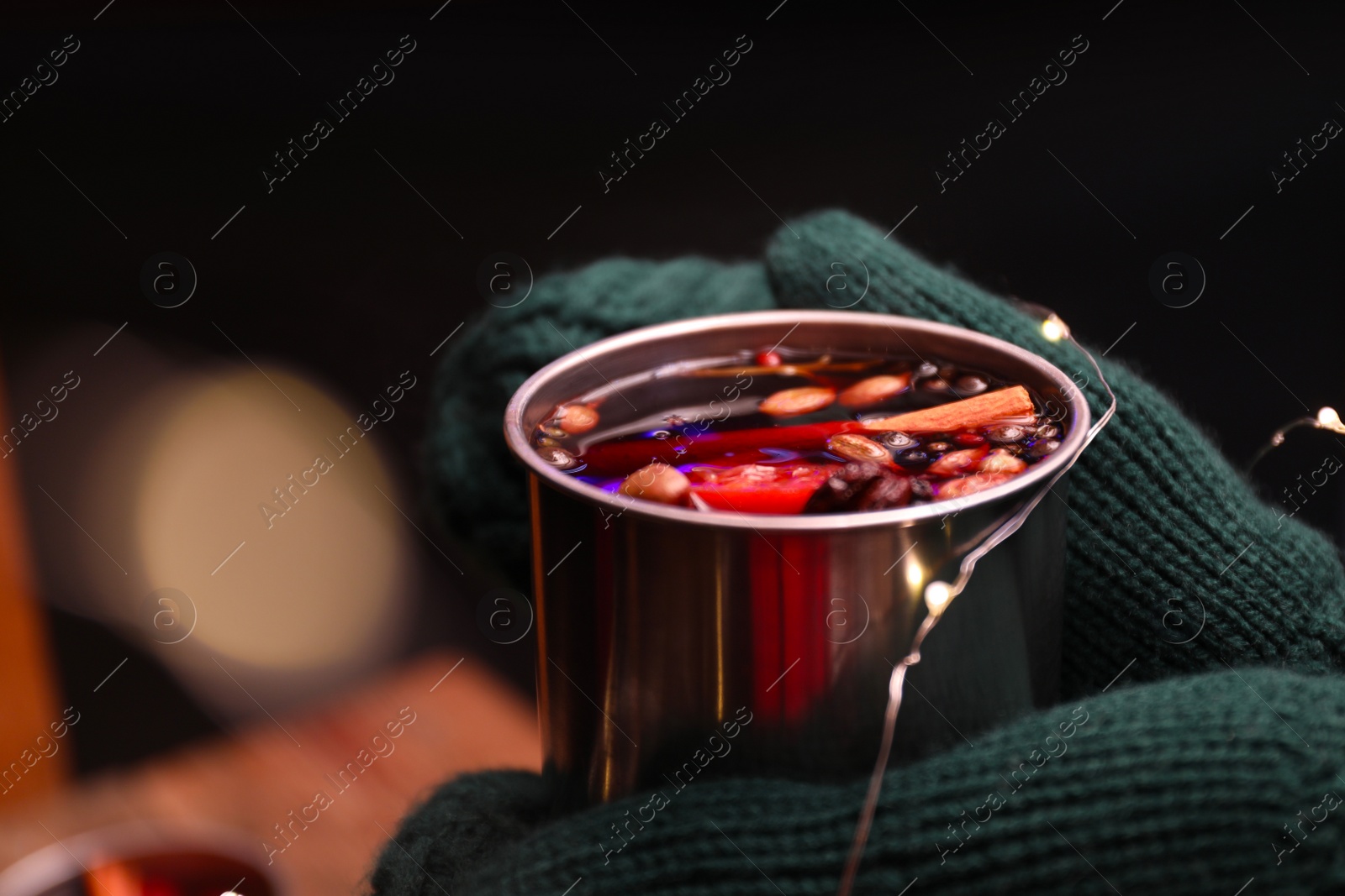 Photo of Person with mug of mulled wine on dark background, closeup