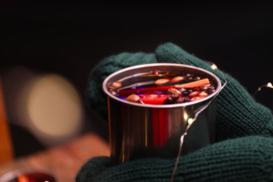 Photo of Person with mug of mulled wine on dark background, closeup