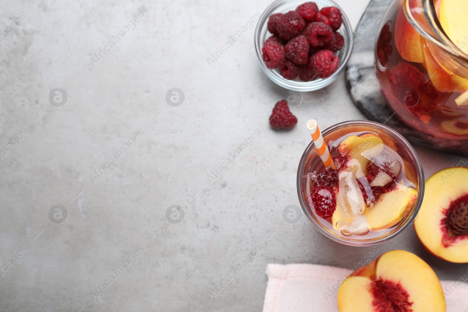 Photo of Flat lay composition of delicious peach lemonade with soda water and raspberries on grey table, space for text. Fresh summer cocktail
