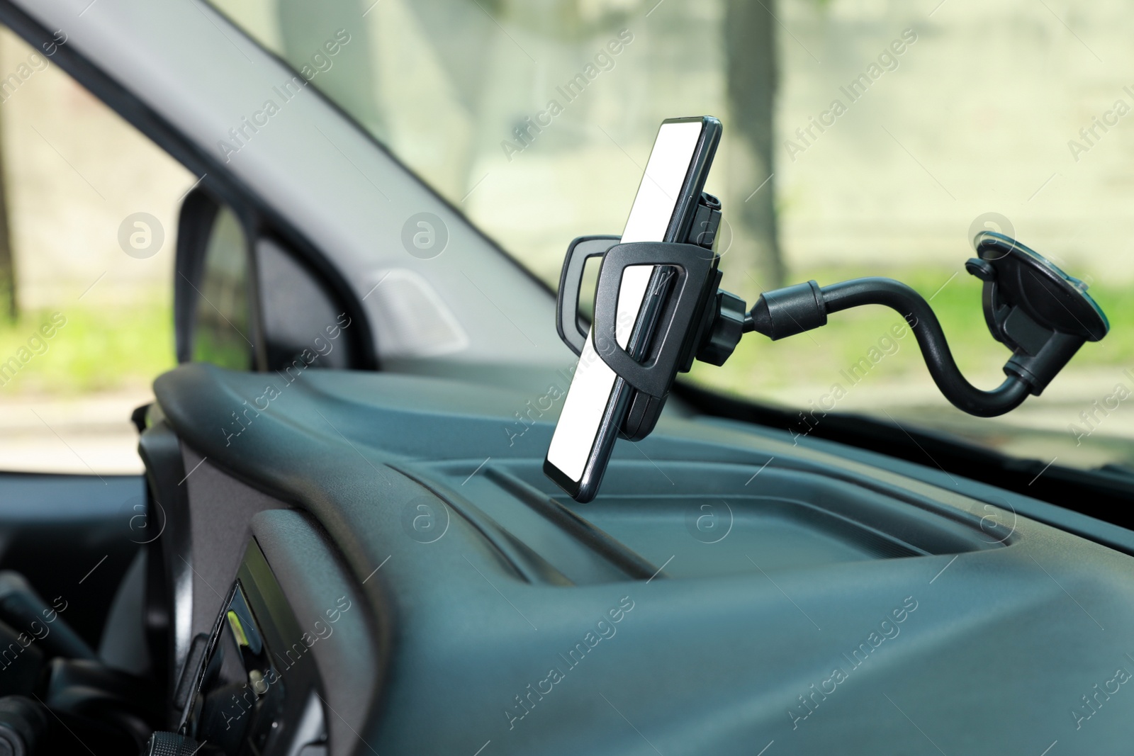 Photo of Car holder with modern mobile phone on windshield of automobile