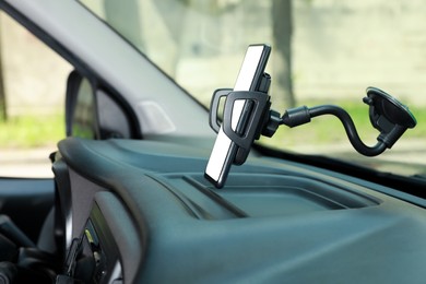 Photo of Car holder with modern mobile phone on windshield of automobile