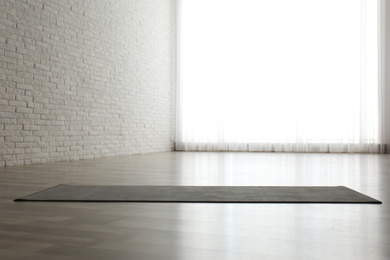 Photo of Unrolled grey yoga mat on floor in room. Space for text