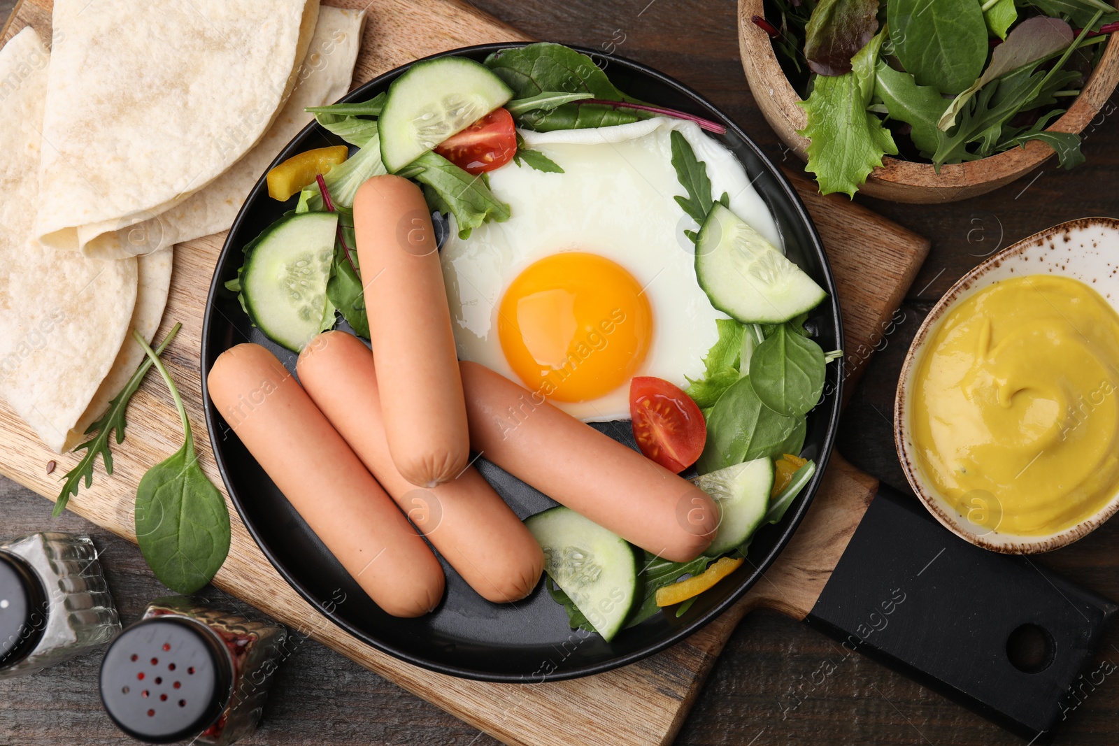 Photo of Delicious breakfast with boiled sausages and fried egg served on wooden table, flat lay