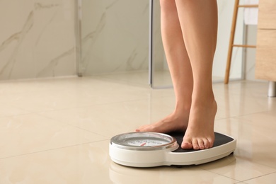 Photo of Woman standing on scales in bathroom, space for text. Overweight problem
