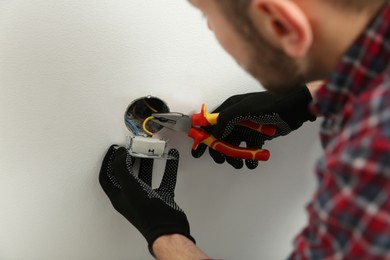 Photo of Electrician with pliers repairing power socket, closeup
