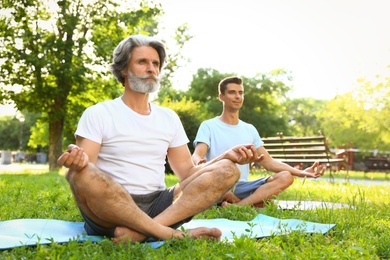 Men practicing morning yoga in sunny park