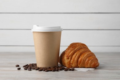 Photo of Coffee to go. Paper cup with tasty drink, croissant and beans on white wooden table