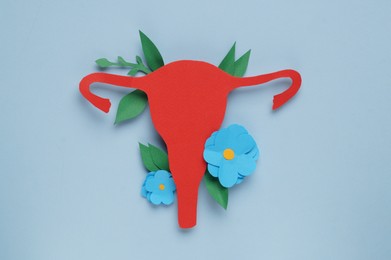 Photo of Woman's health. Paper uterus and flowers on light blue background, flat lay