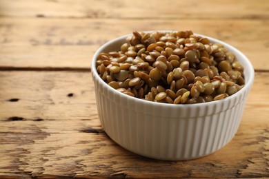 Photo of Delicious lentils in bowl on wooden table, closeup. Space for text