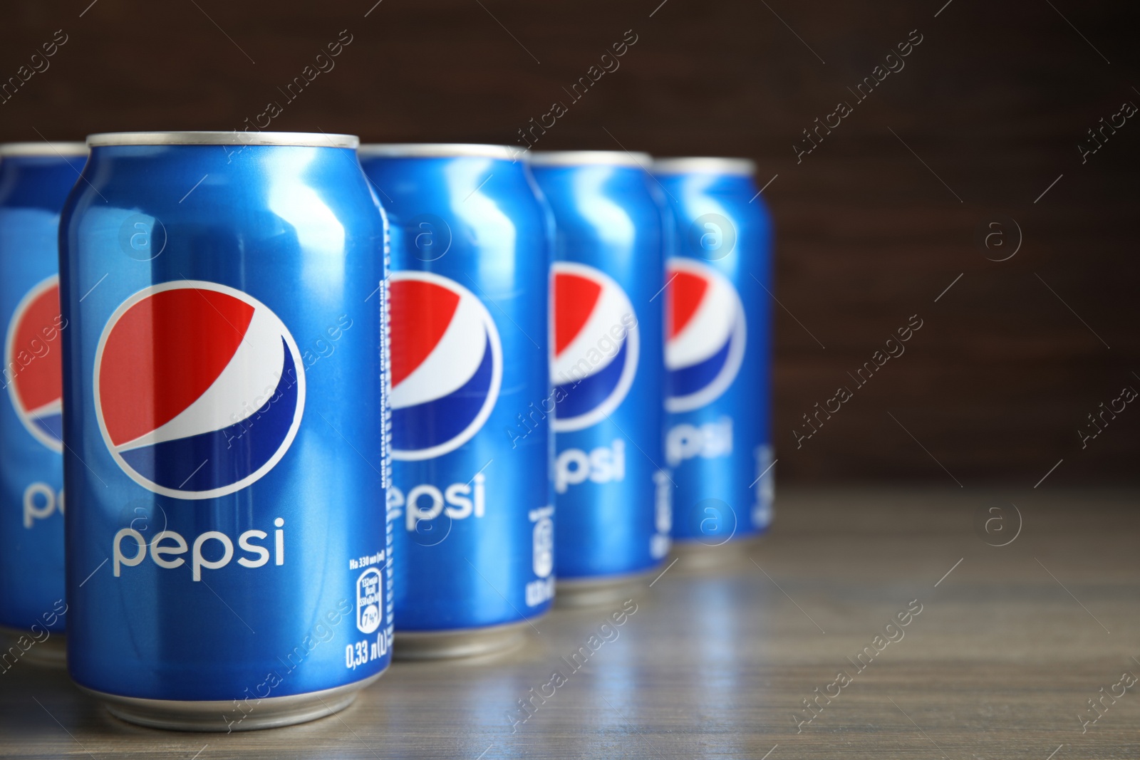 Photo of MYKOLAIV, UKRAINE - FEBRUARY 9, 2021: Many cans of Pepsi on wooden table, space for text
