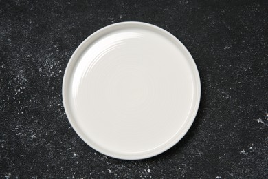 One ceramic plate on black textured table, top view