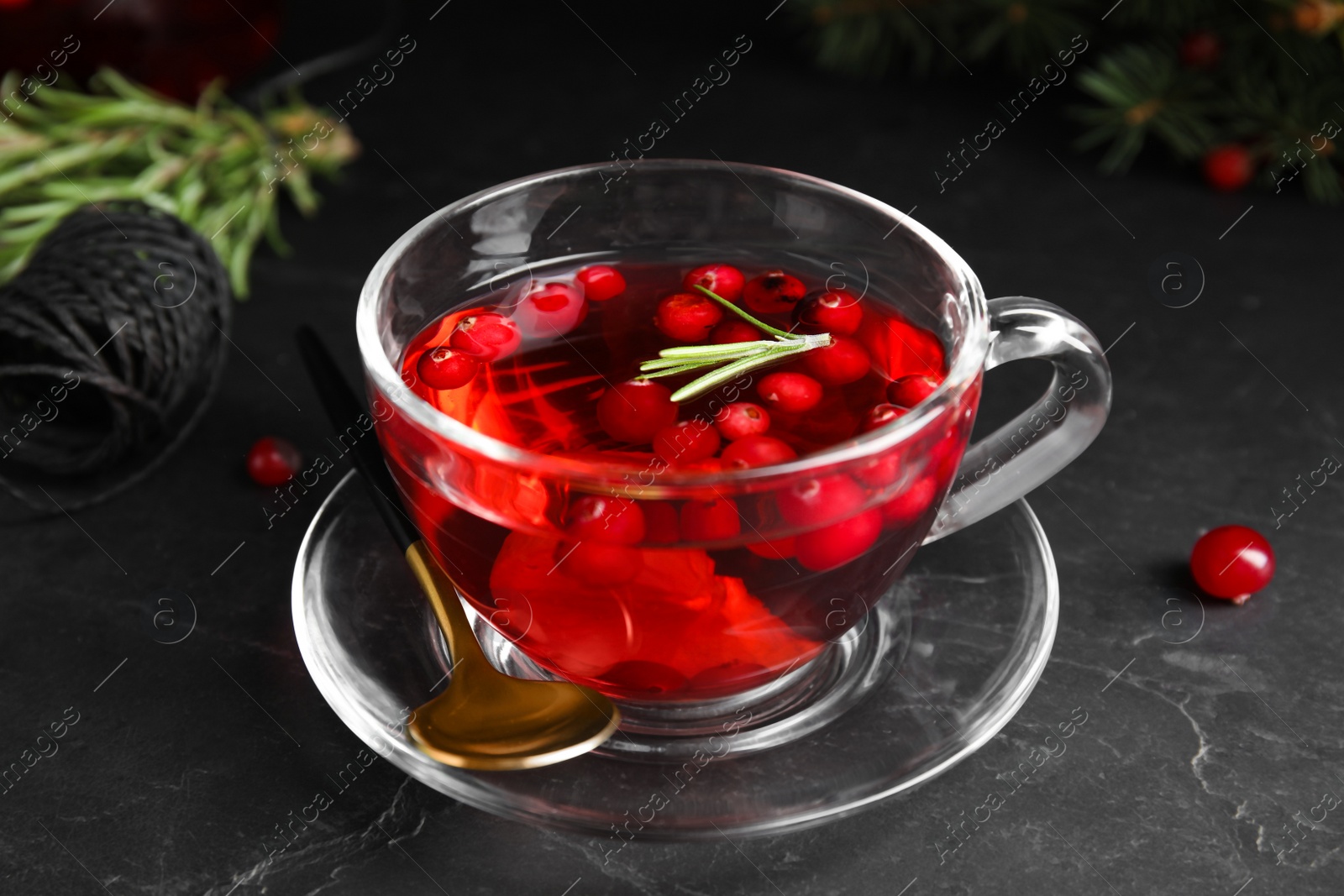 Photo of Tasty hot cranberry tea with rosemary and lemon on black table