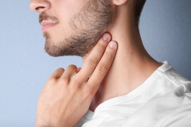 Young man checking pulse on color background