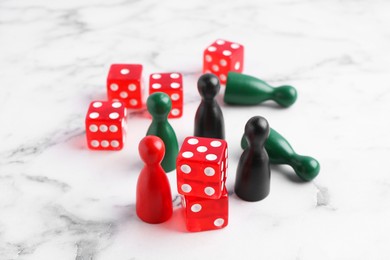 Photo of Red dices and color game pieces on white marble table