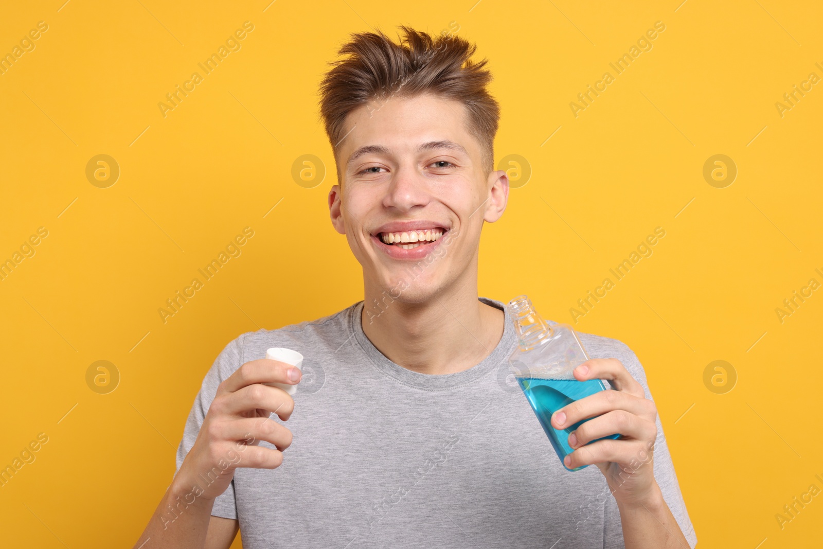 Photo of Young man with mouthwash on yellow background