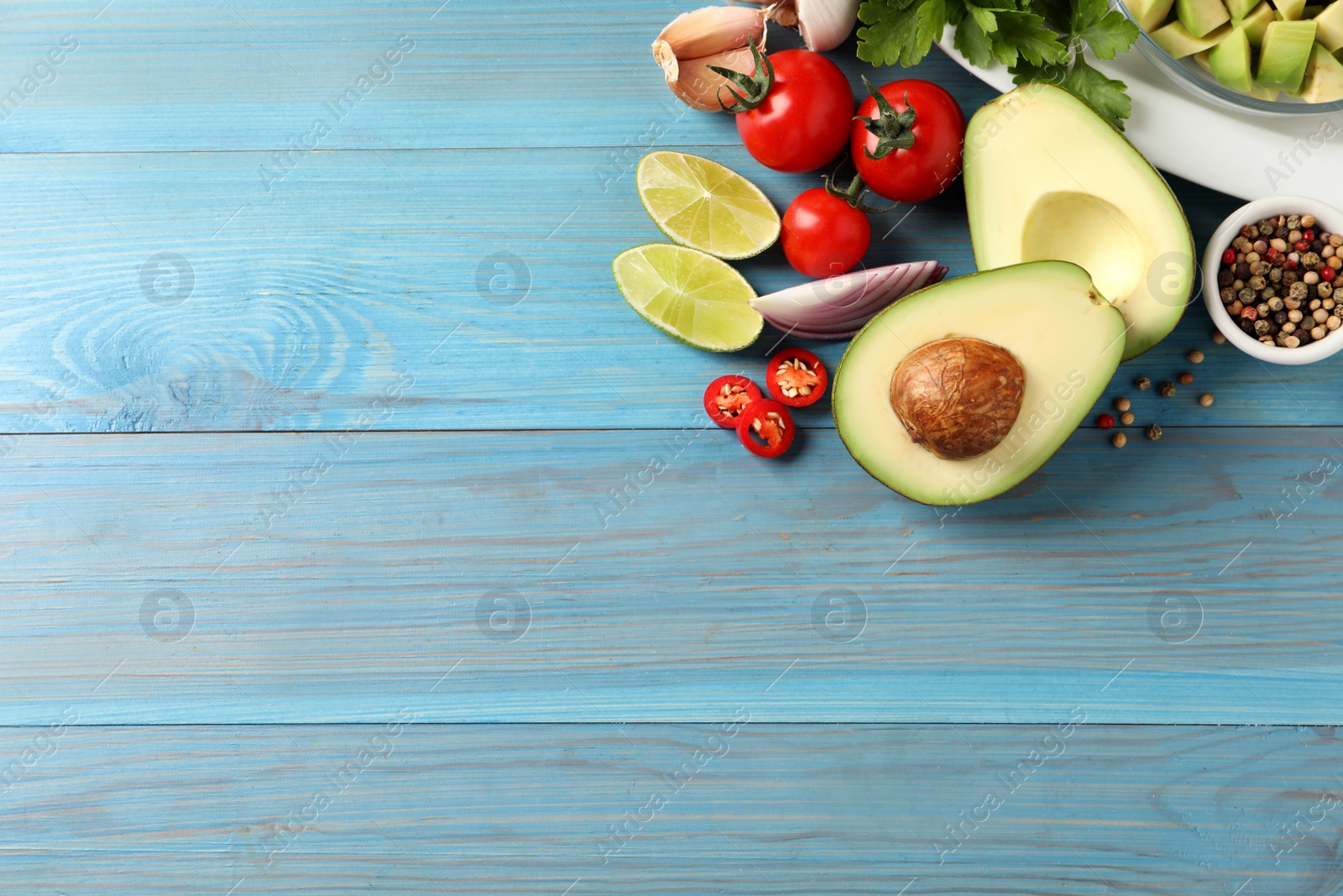 Photo of Fresh guacamole ingredients on light blue wooden table, flat lay. Space for text