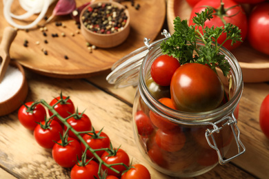 Photo of Pickling jar with fresh ripe cherry tomatoes and spices on wooden table, closeup