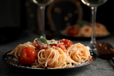 Tasty pasta with basil, tomatoes and cheese on grey table. Closeup