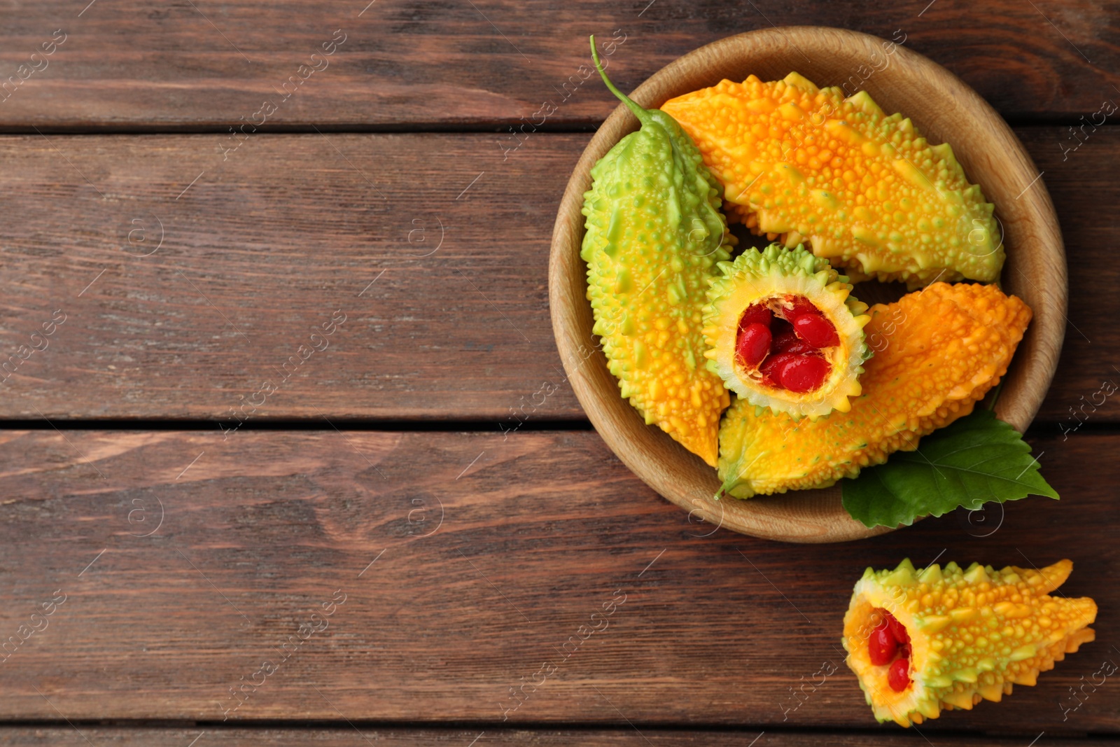 Photo of Fresh bitter melons on wooden table, flat lay, Space for text