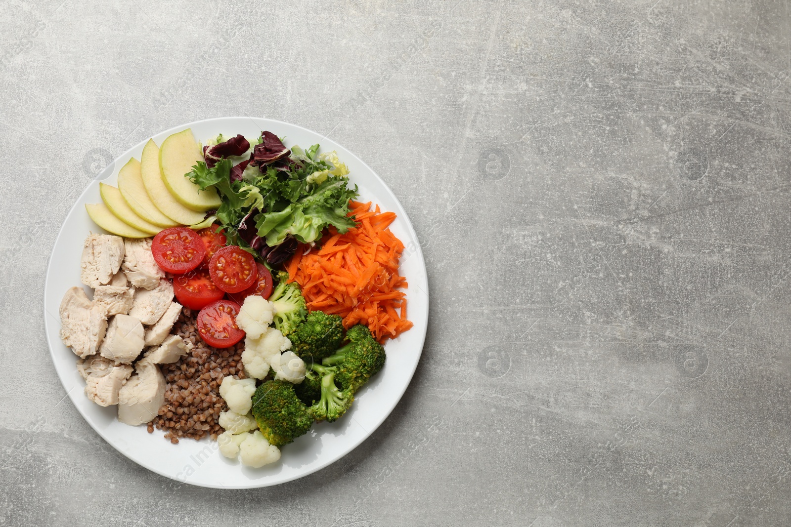 Photo of Balanced diet and healthy foods. Plate with different delicious products on grey table, top view. Space for text