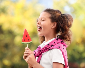 Cute little girl with tasty candy outdoors