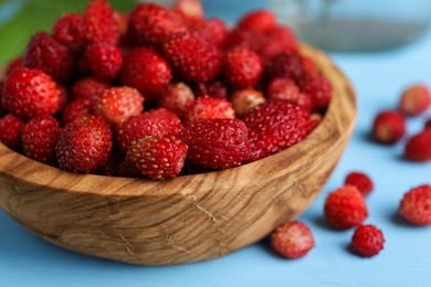 Photo of Fresh wild strawberries in bowl on light blue table, closeup