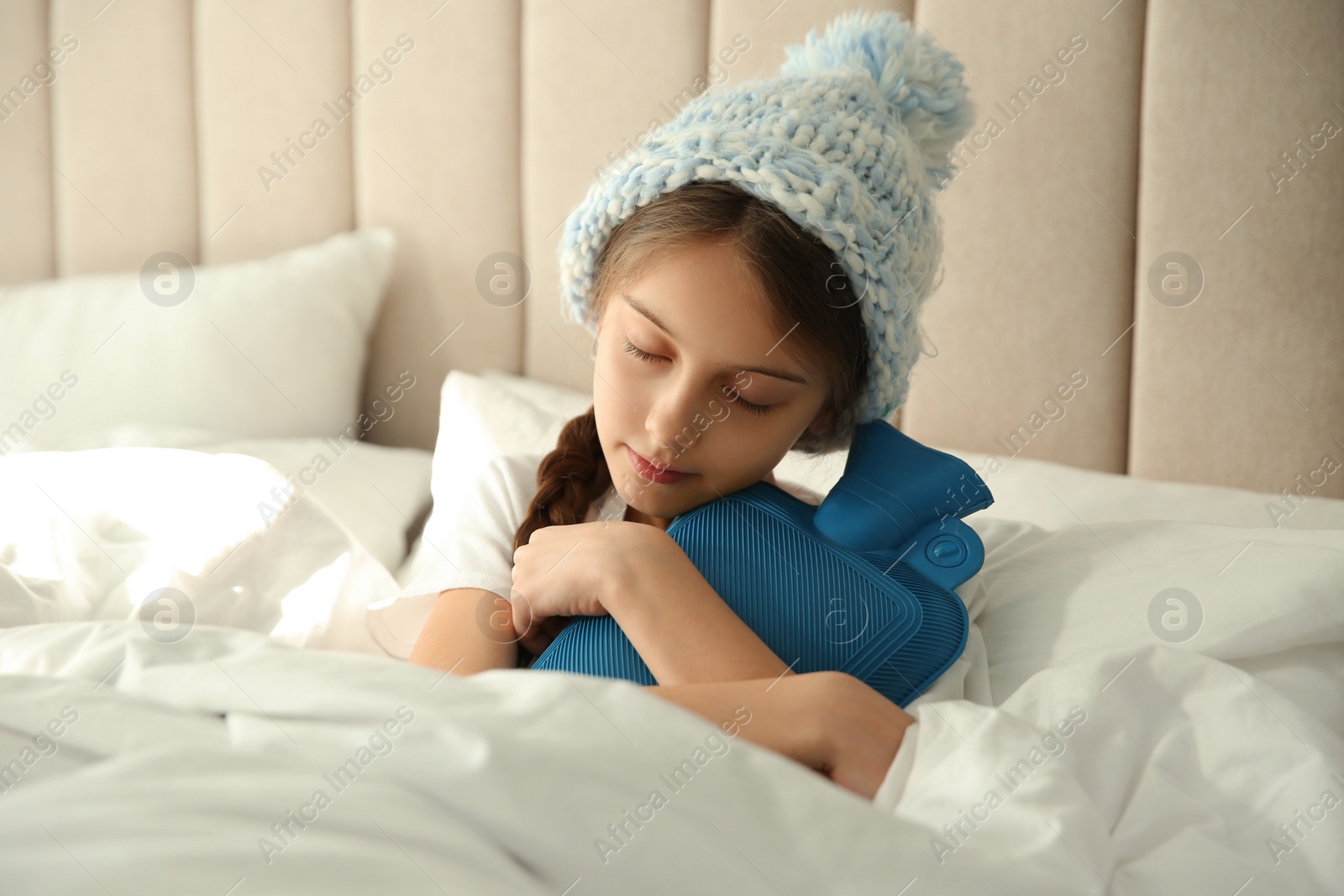 Photo of Ill girl with hot water bottle suffering from cold in bed at home