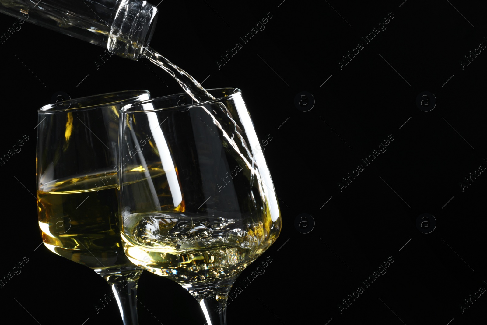 Photo of Pouring tasty aromatic wine in glass on black background, closeup. Space for text