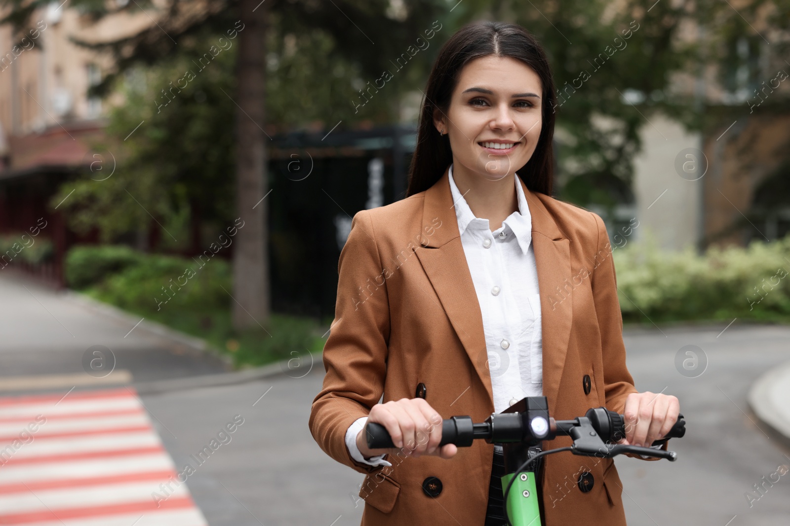 Photo of Businesswoman riding electric kick scooter on city street, space for text