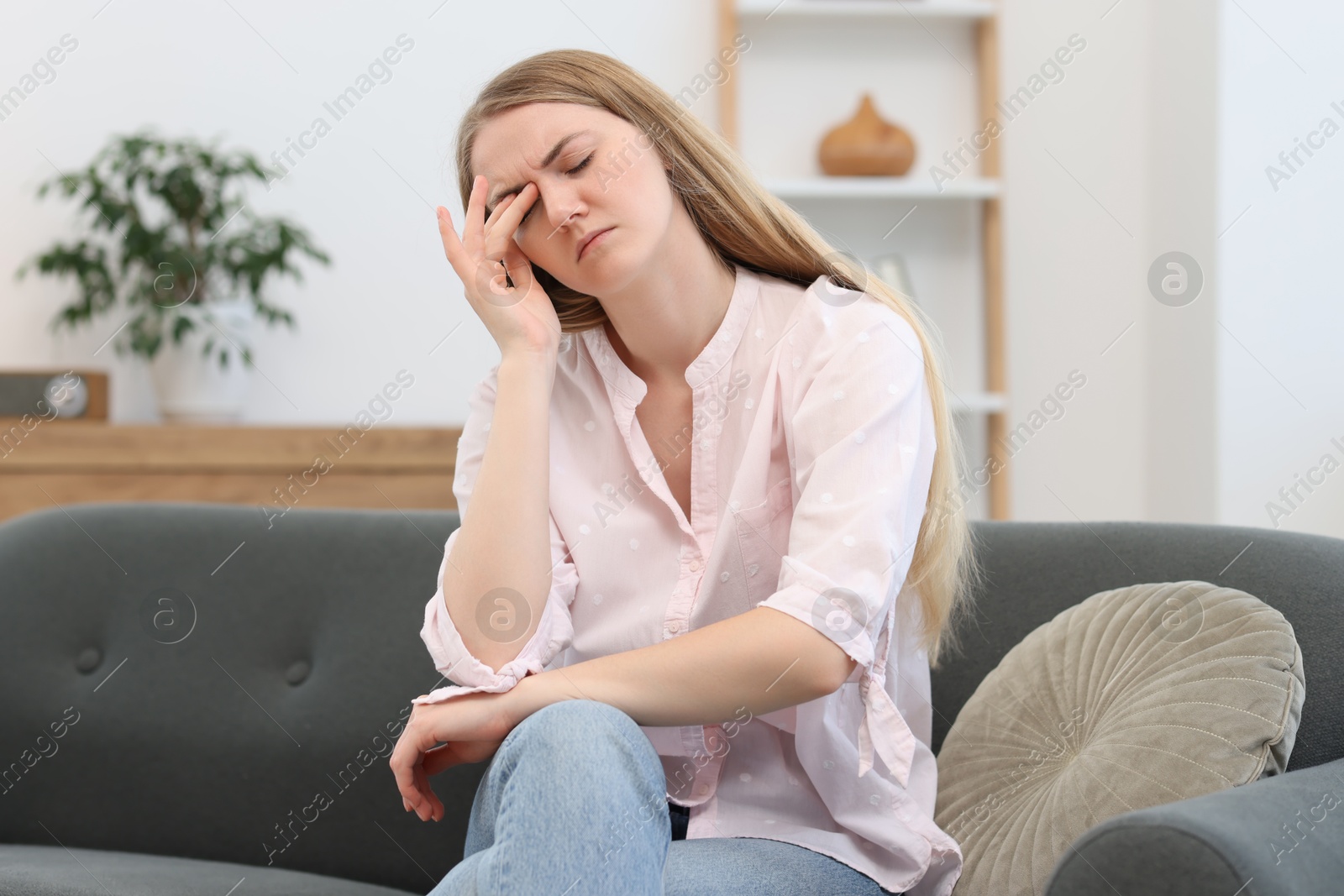 Photo of Overwhelmed young woman suffering from headache at home