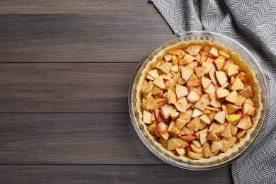 Top view of raw dough with apple slices on wooden table, space for text. Baking pie