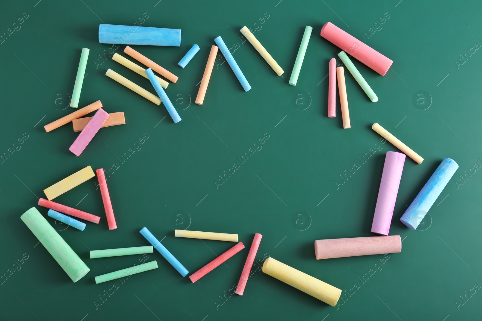 Photo of Color pieces of chalk on green background, top view