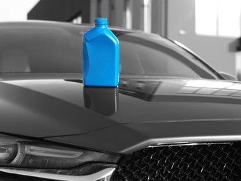 Blue canister with motor oil on hood of car outdoors
