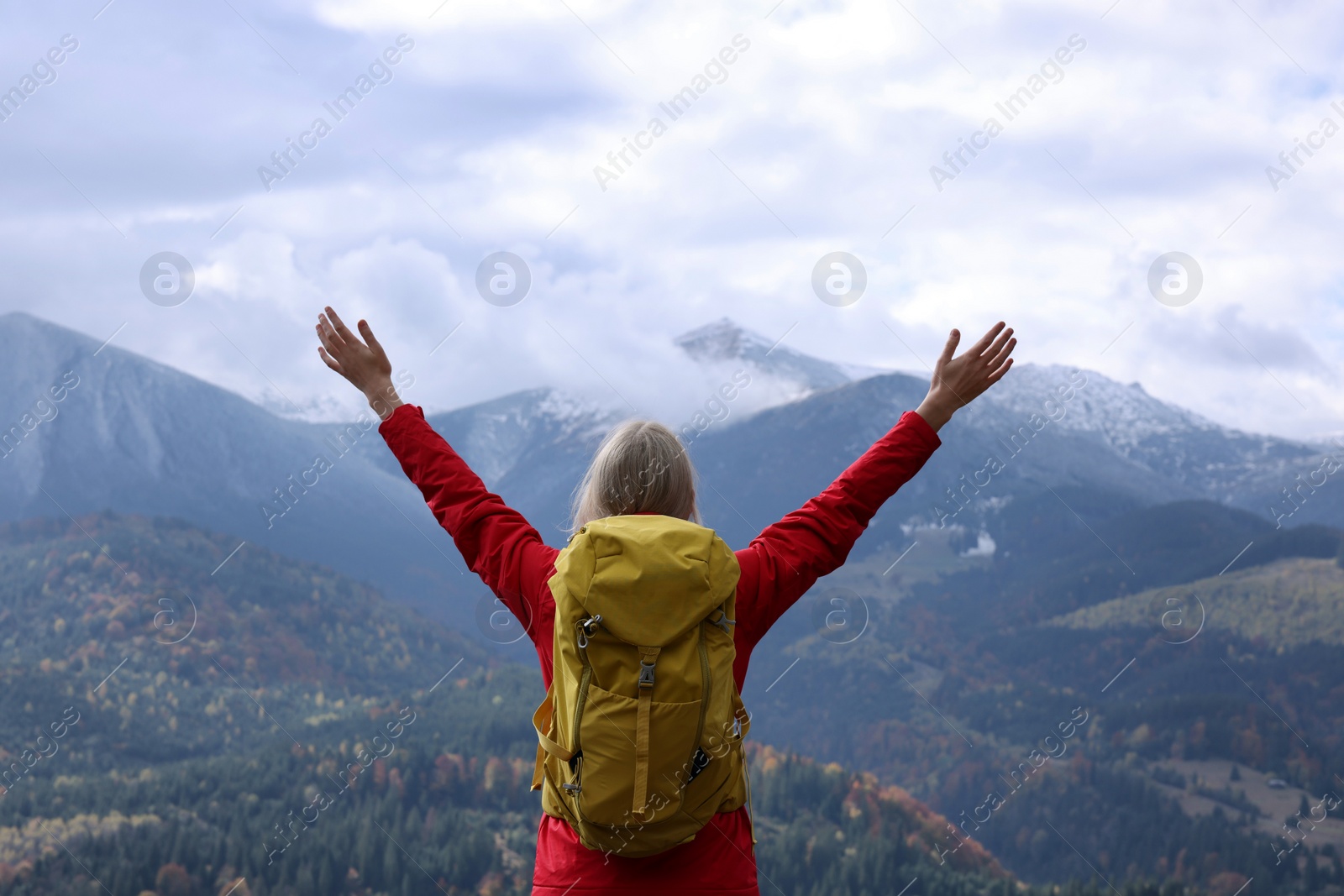 Photo of Happy woman with backpack admiring mountain landscape, back view. Feeling freedom