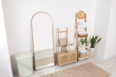 Photo of Stylish decorative ladders with clean towels and other furniture in room