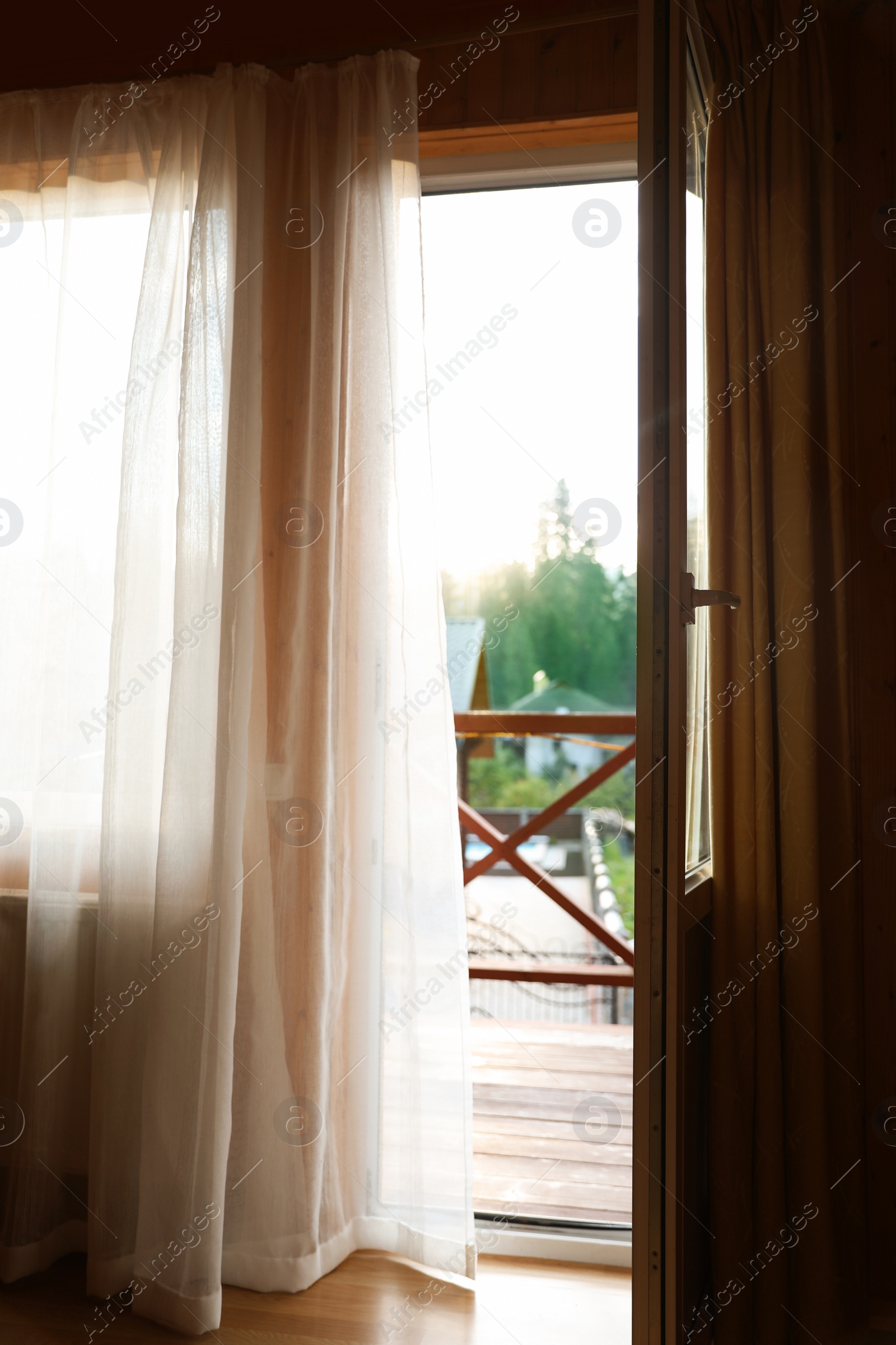 Photo of Open balcony door with curtain in apartment